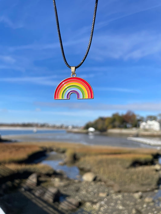 rainbow pendant on wax cord held up against the blue sky