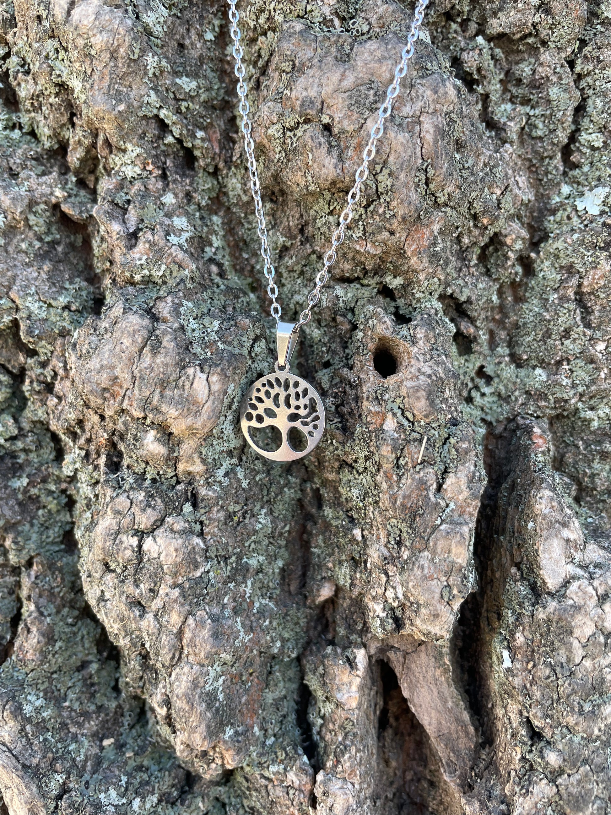 Tree of life stainless steel necklace against tree